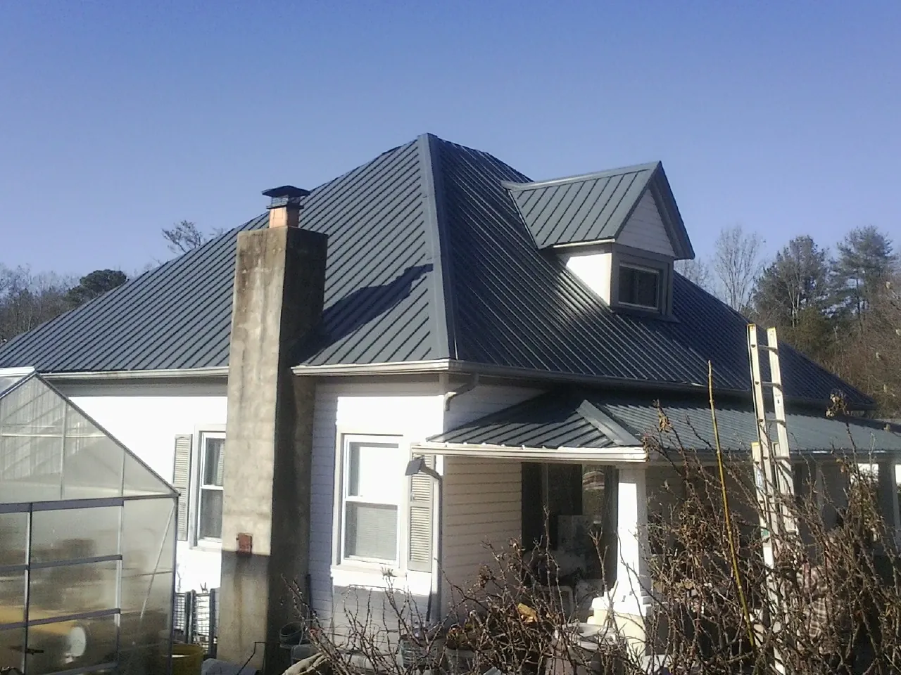 Dark blue standing seam metal roof on a white farmhouse with dormer — Slate & Tile Roof Repair by Roofing Brothers in Siletz