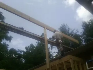 Carpenter setting a ridge beam over a new addition frame — Ice Dam Removal by Roofing Brothers in Siletz