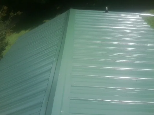 New green metal panels meeting at the ridge of a roof — Flat Roof Repair work by our crew in Siletz