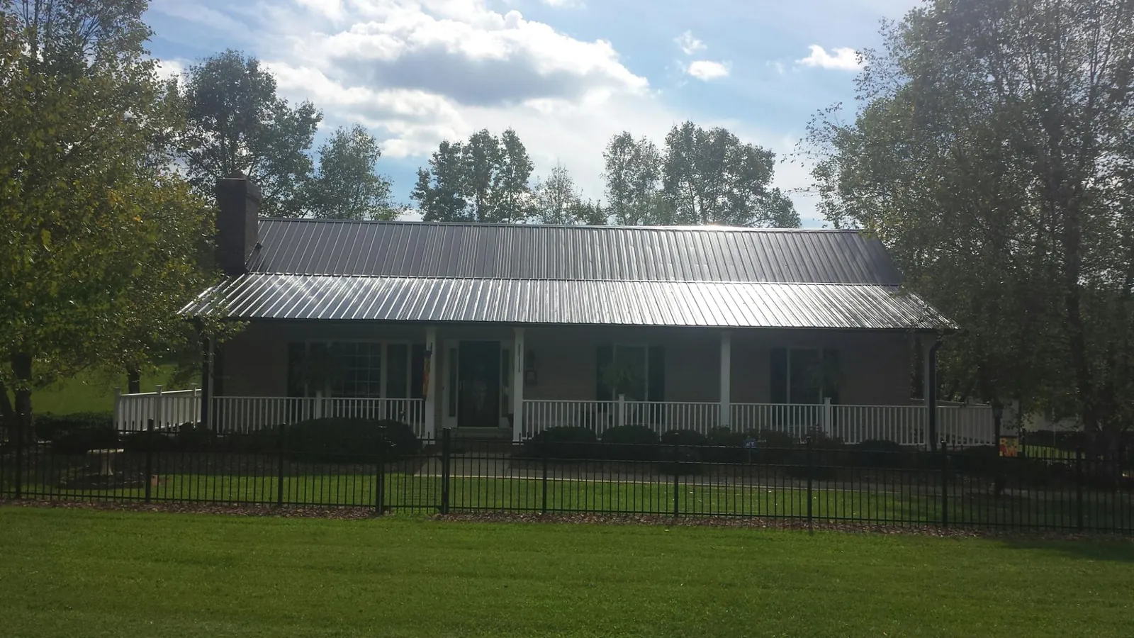 Gray metal roof on a brick ranch with a full width front porch — Gutter Guard Installation work by our crew in Siletz