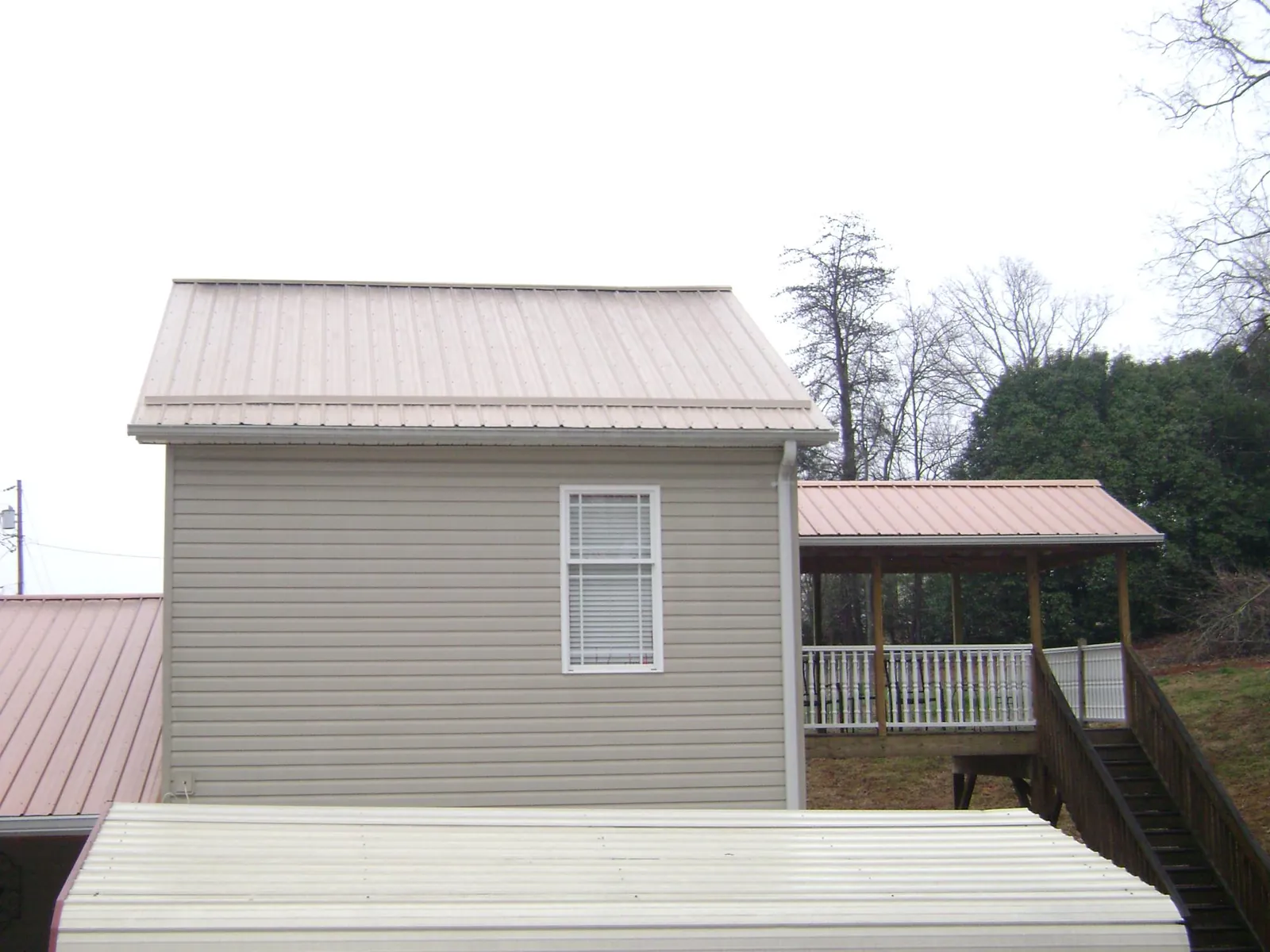 Tan metal roofs on a two story addition and attached porch, from a Roof Replacement job in Siletz