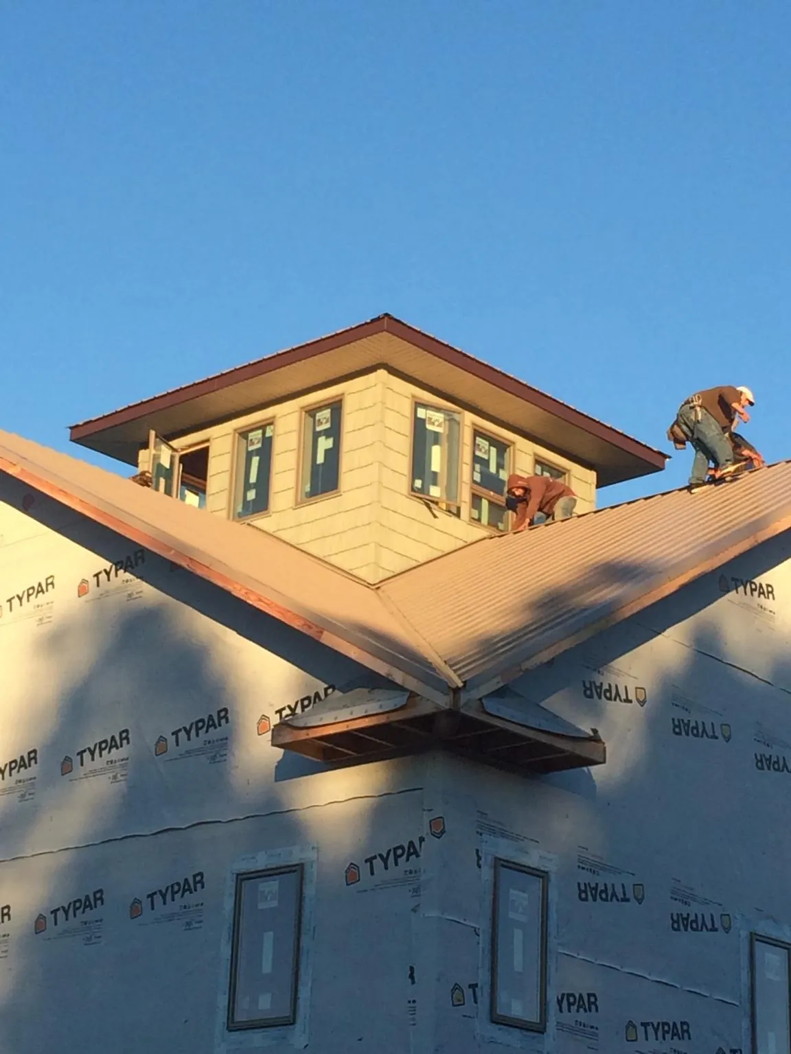Roofers working around a rooftop cupola on a new metal roof at sunset — Roof Waterproofing in Siletz by Roofing Brothers